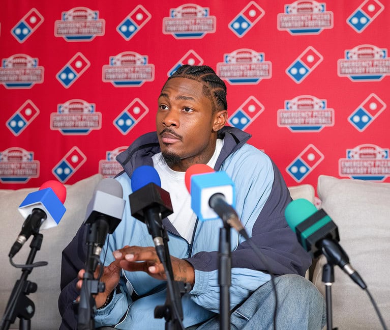 Image of Stefon Diggs at a press conference with Dominos backdrop reporting on Franchise News about pizza