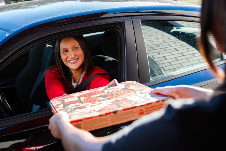 Pizza Hut Drive Thru for AI Franchise Industry News Article. Shows person being a handed a pizza box while they are in their car.