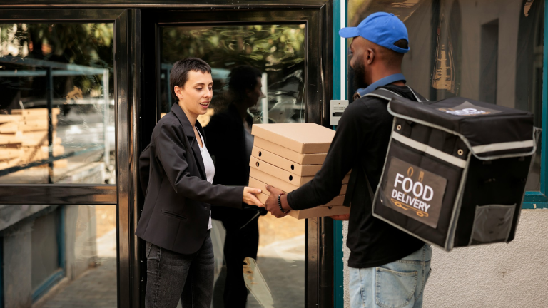 Two people one delivering and one receiving pizza on last mile logistics route