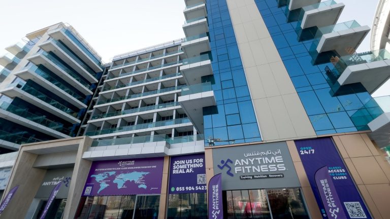Franchising Beyond Borders: Building Global Success Through Strategy and Shared Values Front exterior of the Anytime Fitness club in Dubai’s Arjan District showing branded purple signage, glass balconies, and “Open 24/7” banners on a modern building façade.