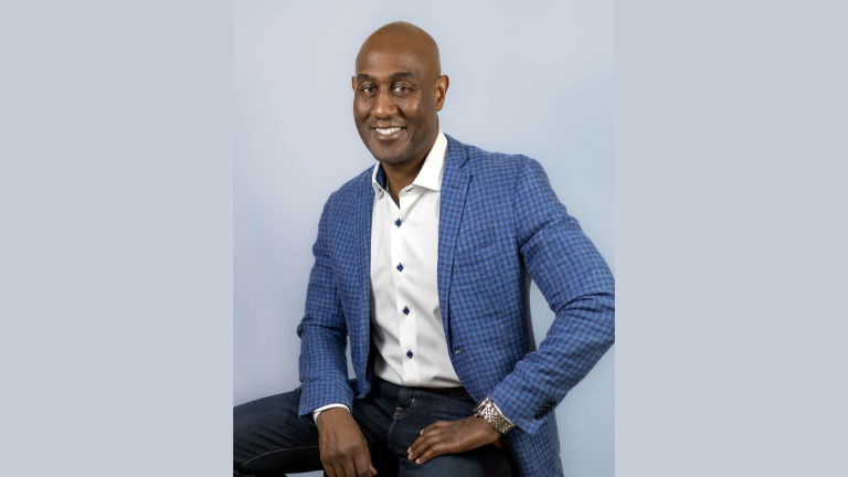 Panera Bread Appoints Earl Ellis as Chief Financial Officer Portrait of Earl Ellis, newly appointed Chief Financial Officer of Panera Bread, wearing a blue checkered blazer and white shirt against a light gray background.