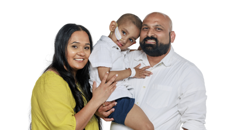 family portrait shows a young child currently undergoing treatment at St. Jude Children’s Research Hospital, held by his father while his mother embraces them both.