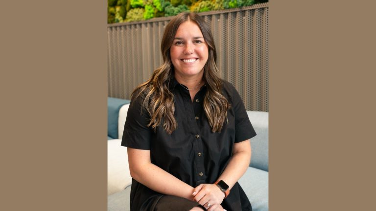 Houston TX Hot Chicken Names Andie Smirl Director of Franchise Sales Smiling person seated in a modern lounge with a green plant wall behind them.