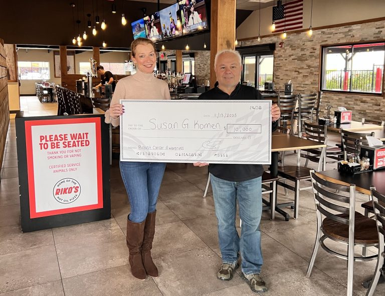 Riko’s Pizza presents a $10,000 check to Susan G. Komen inside a Riko’s restaurant