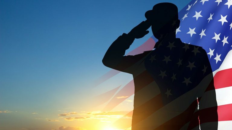 Silhouette of a U.S. service member saluting at sunrise with an American flag overlay.