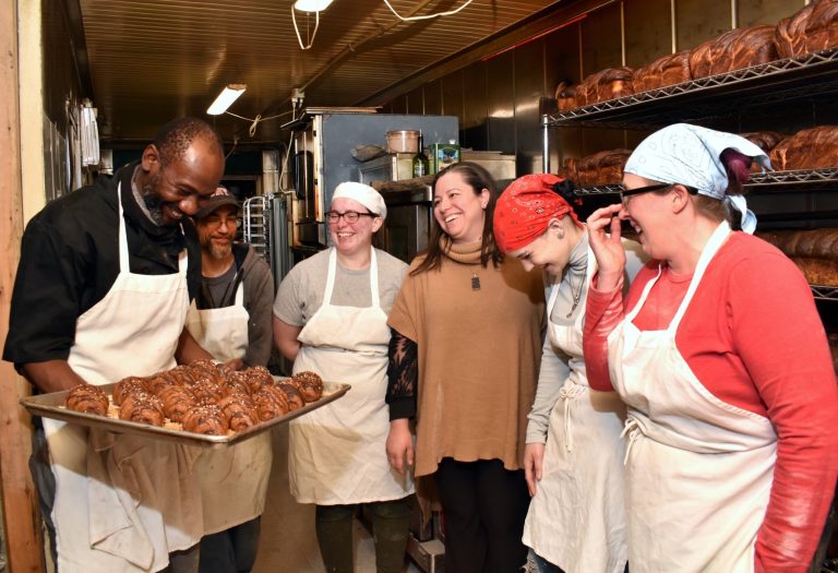 See & Be Kitchen’s “First Rise Challenge” Crafted To Find Its Founding Franchisee Bakers laugh together as a colleague presents a tray of fresh chocolate pastries in a busy kitchen