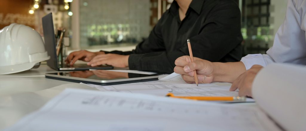 Franchise team reviews test-fit plans with laptop and hard hat on table