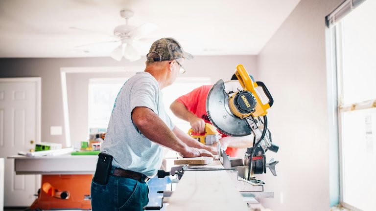 Contractors cutting lumber with a miter saw during a home renovation