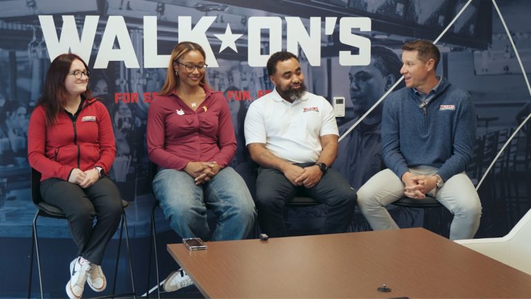 Trinity, Hannah and Chris seated for a Walk-On’s Blue Chip conversation in front of a branded wall