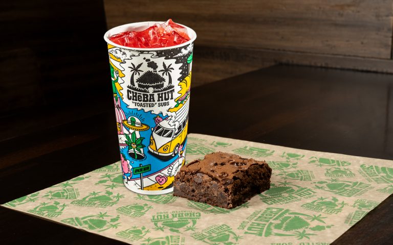 Cheba Hut branded drink cup and chocolate brownie on branded paper