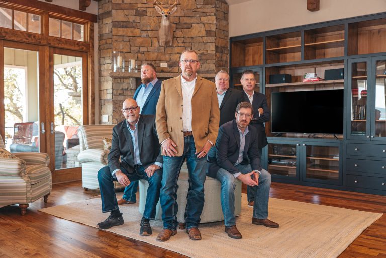 Franchise Now leadership team; two seated in front, four standing behind in a lodge-style living room