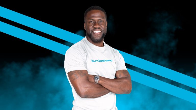 Kevin Hart Walks Into Burn Boot Camp; Everyone Gets Stronger Kevin Hart in a Burn Boot Camp T-shirt, smiling with arms crossed against a branded backdrop