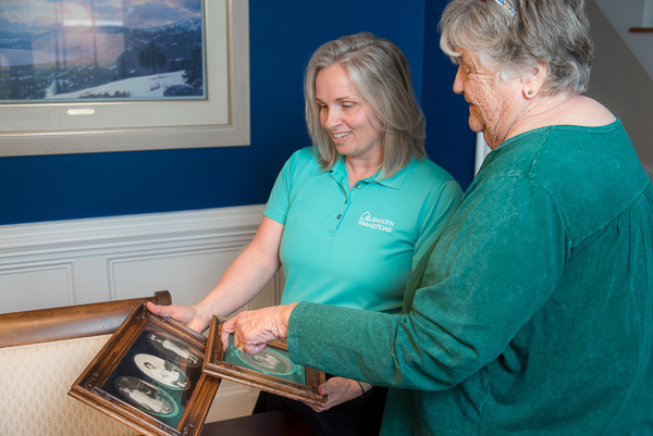 Smooth Transitions team member helps a senior review framed family photos during the downsizing and move planning process