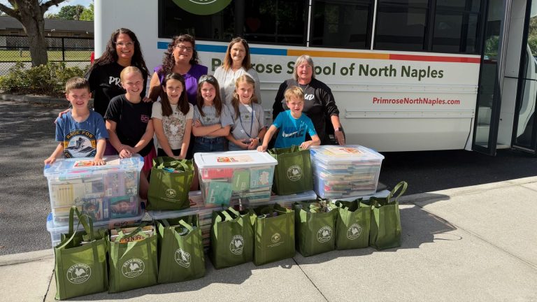 Children and staff from Primrose School of North Naples pose with donated books in front of a school bus
