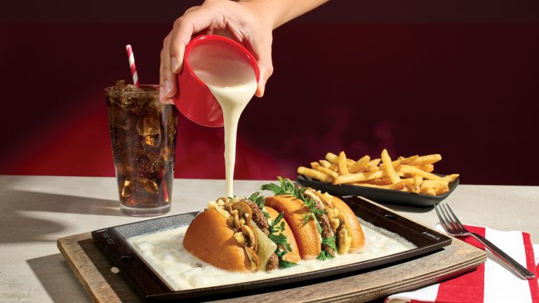 Tableside cheese fondue poured over TGI Fridays burgers on a sizzling cast-iron skillet
