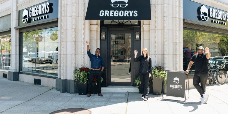 Gregorys Coffee team members wave outside a Gregorys Coffee storefront