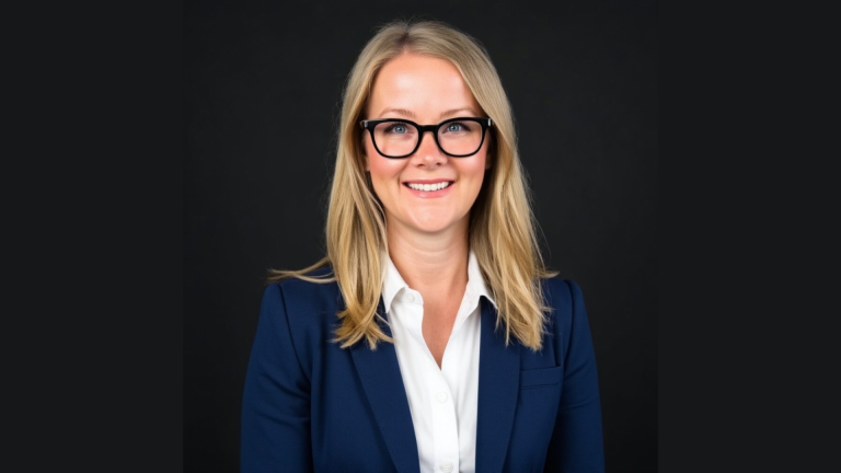 Sara Schmillen professional headshot in navy blazer and glasses
