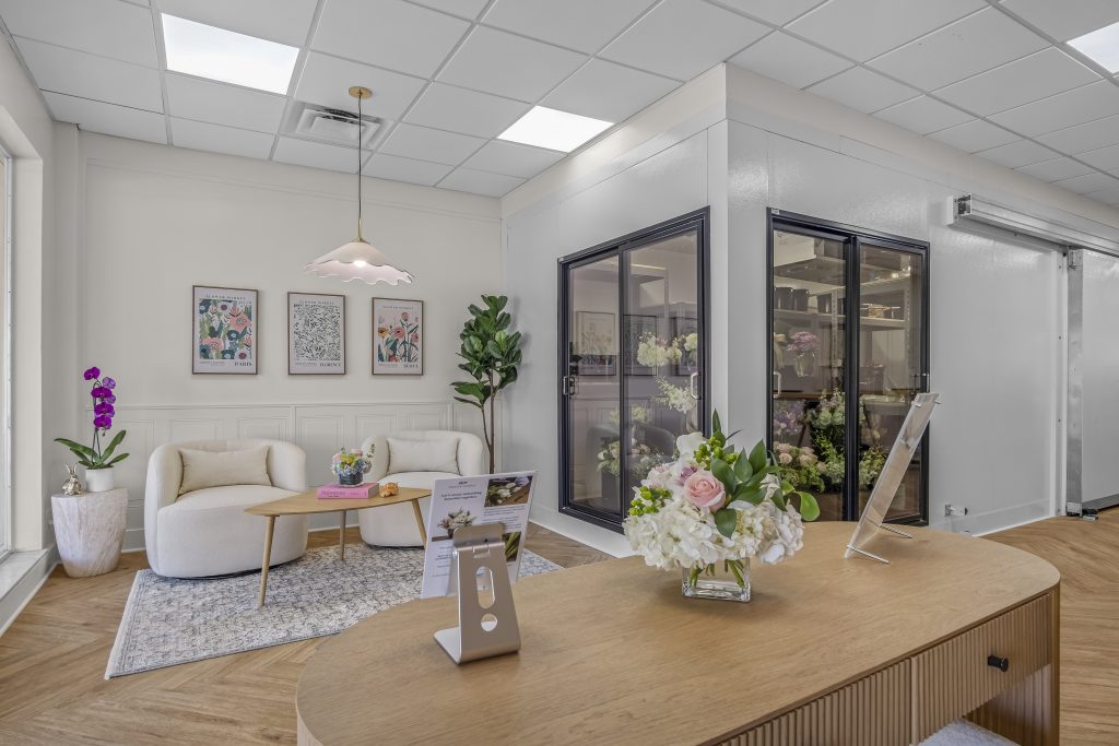 The modern and elegantly designed interior of a French Florist franchise location featuring a curved reception desk, fresh floral arrangements, and a walk-in cooler.