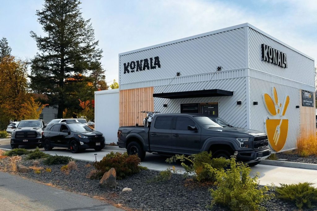 Vehicles lined up in the drive-through lane at a Konala modular restaurant location with bold exterior branding
