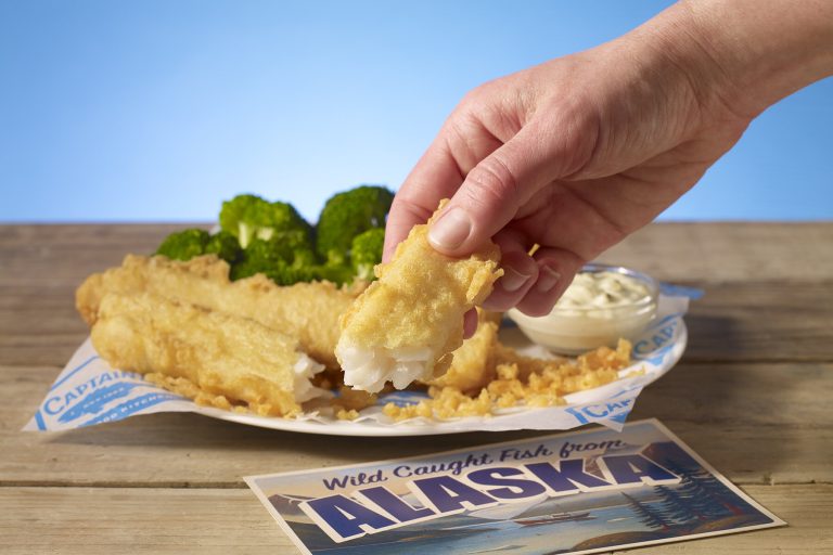 Captain D’s Introduces Wild Caught Batter Dipped Fish from Alaska Hand holding a piece of Captain D’s Wild Caught Batter Dipped Fish from Alaska with tartar sauce