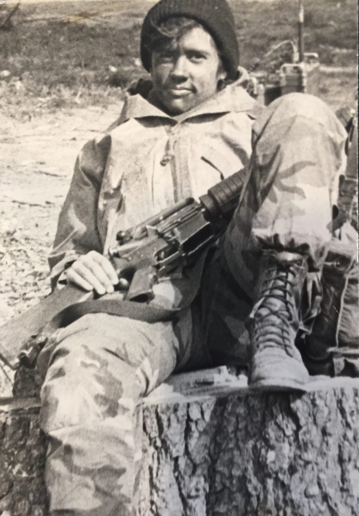 Mary Kennedy Thompson in military field gear seated on a tree stump during field training exercises