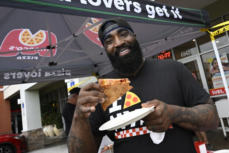 God Shammgod enjoys a slice of Marco’s Pizza NY Style Pizza during a promotional event in Orlando