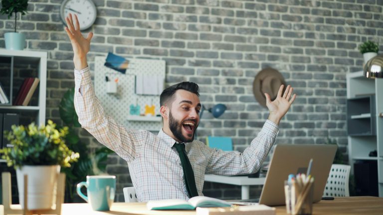 Business owner celebrates franchise ownership success at his desk