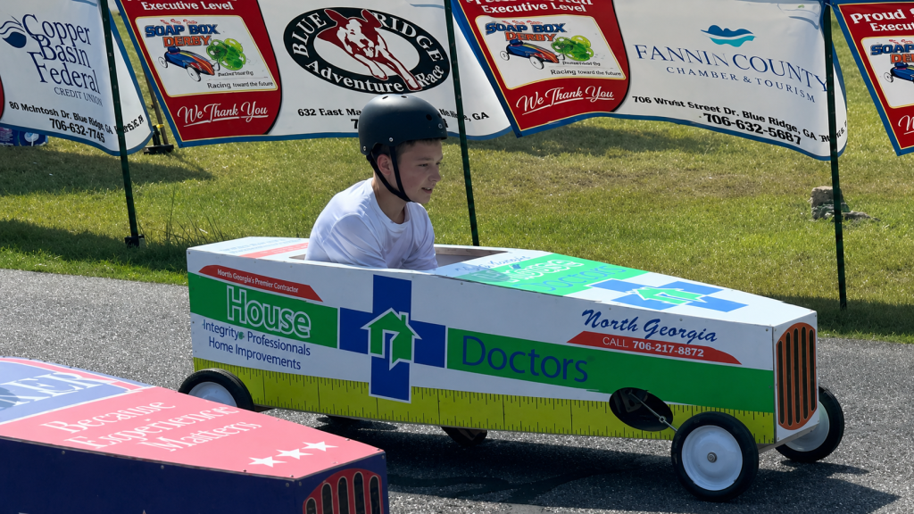 A young racer in a House Doctors-branded soapbox derby car at the Blue Ridge Adventure Race in North Georgia