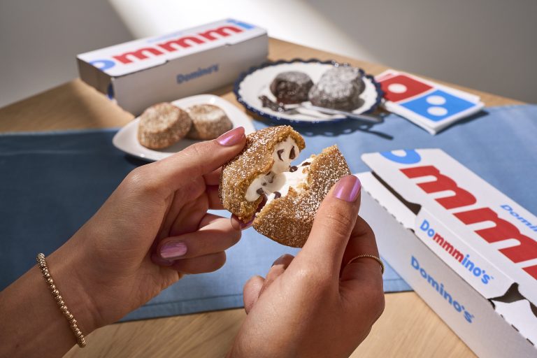Hands pull apart a Domino's S'mores Lava Cake to reveal its gooey marshmallow and chocolate filling.