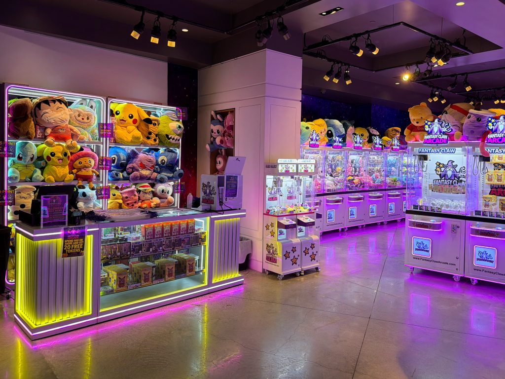Fantasy Claw Arcade Hawaii interior showing the prize counter and rows of claw machines under purple ambient lighting