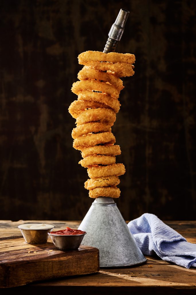 Ford's Garage onion ring tower stacked on a vintage oil funnel with dipping sauces