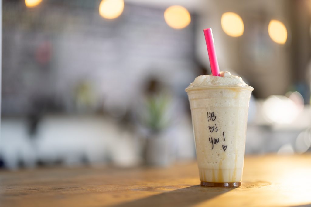 HB Protein Smoothies cup with a handwritten "HB loves you" note on a wooden table.