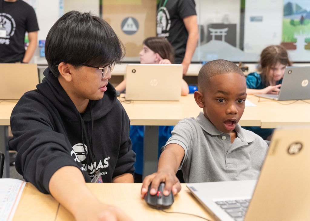 A Code Ninjas student reacts with surprise while working on a laptop coding project with an instructor.