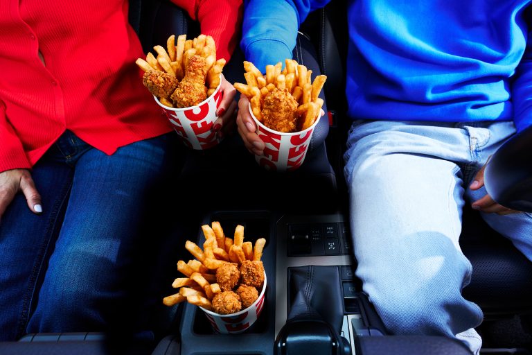 KFC Go Buckets with fried chicken and fries held by passengers inside a vehicle