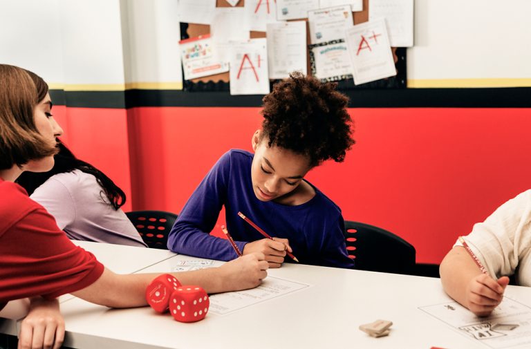 A student works on a math worksheet with an instructor at a Mathnasium learning center.